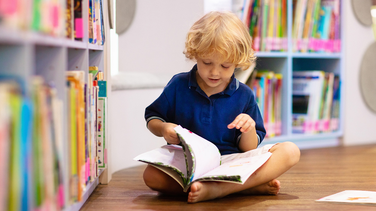 Kid independently reading in a library.